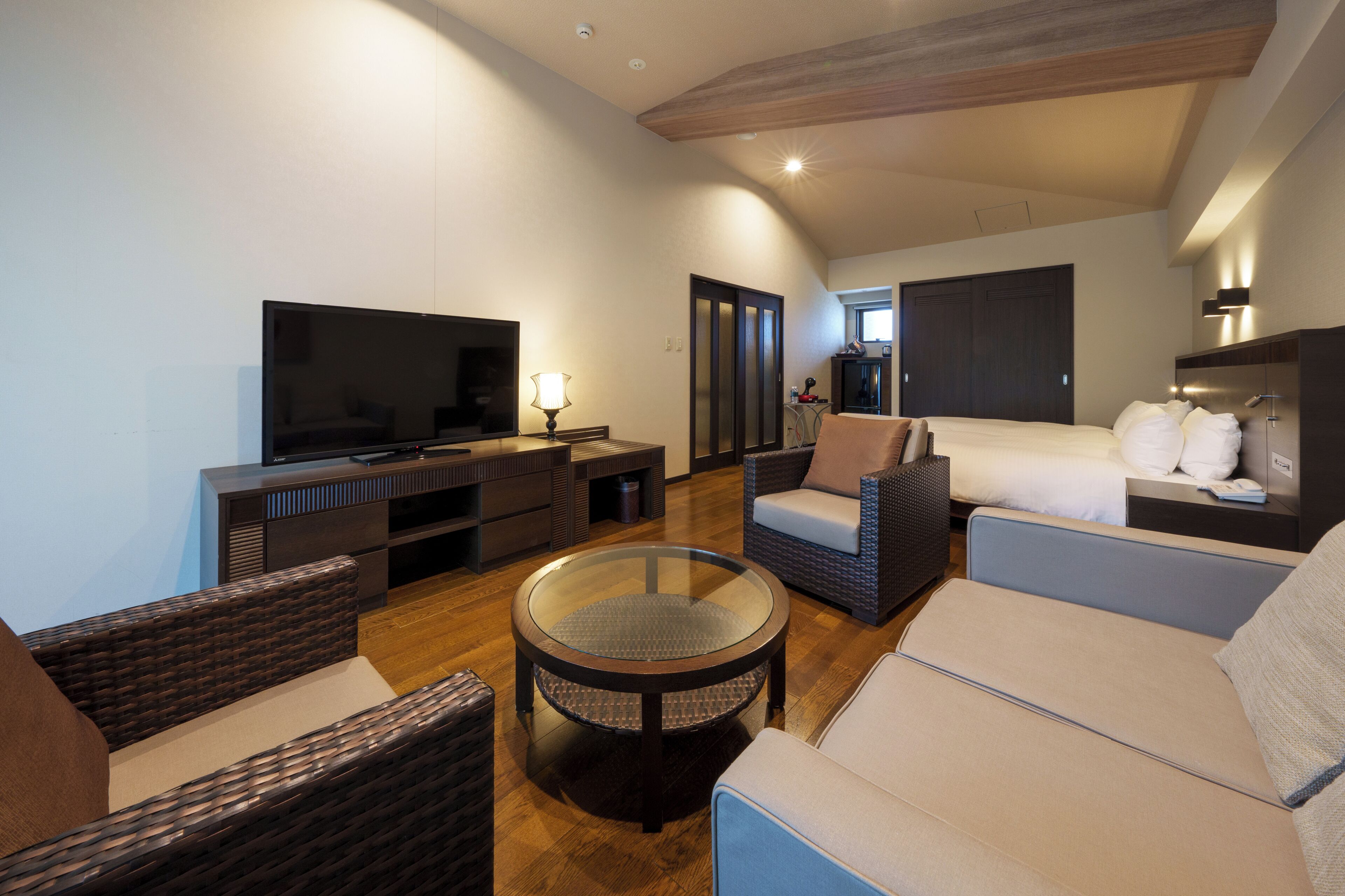 A living room with a television, seating, and a glass coffee table.