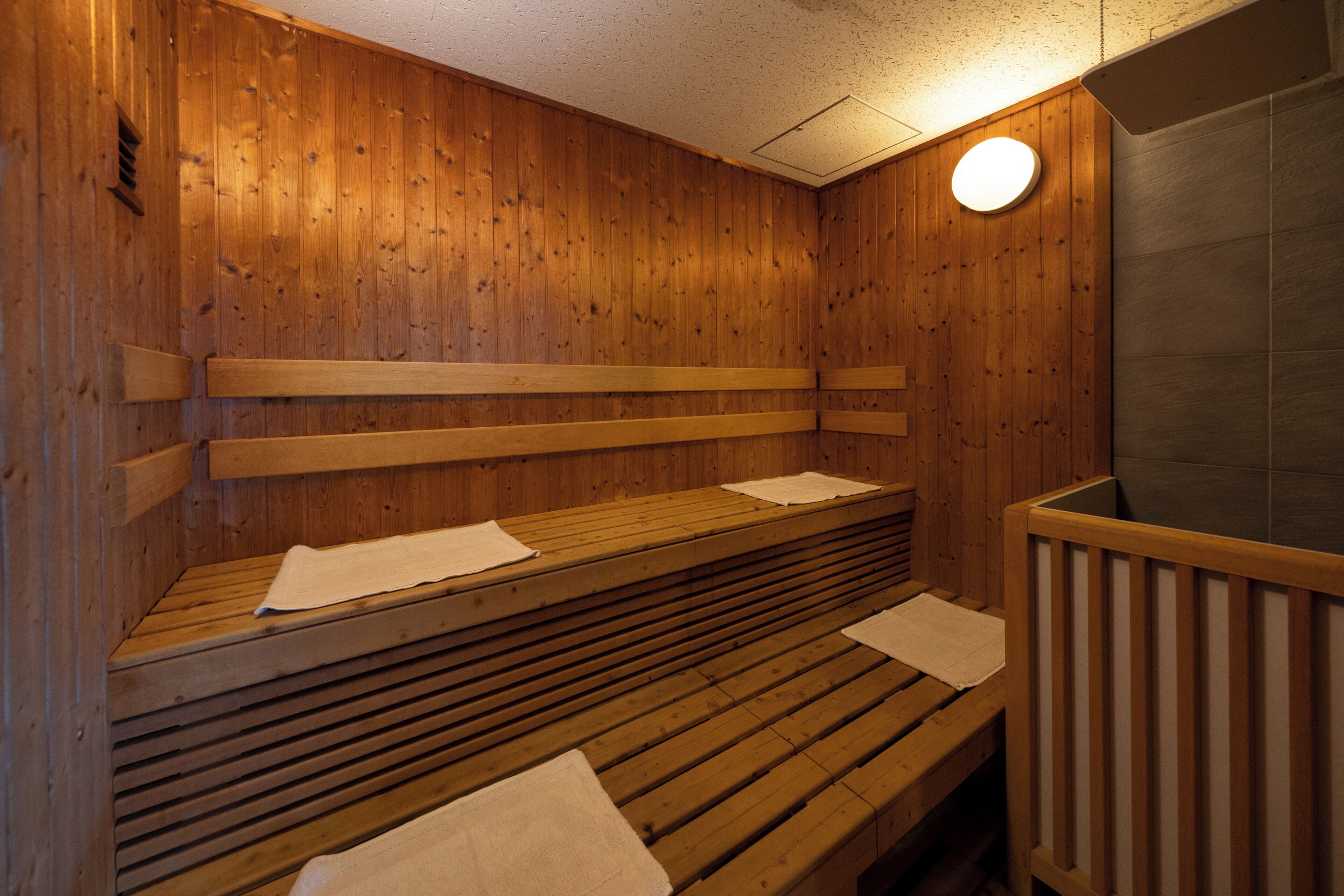 A sauna with wooden benches and a tiled wall.