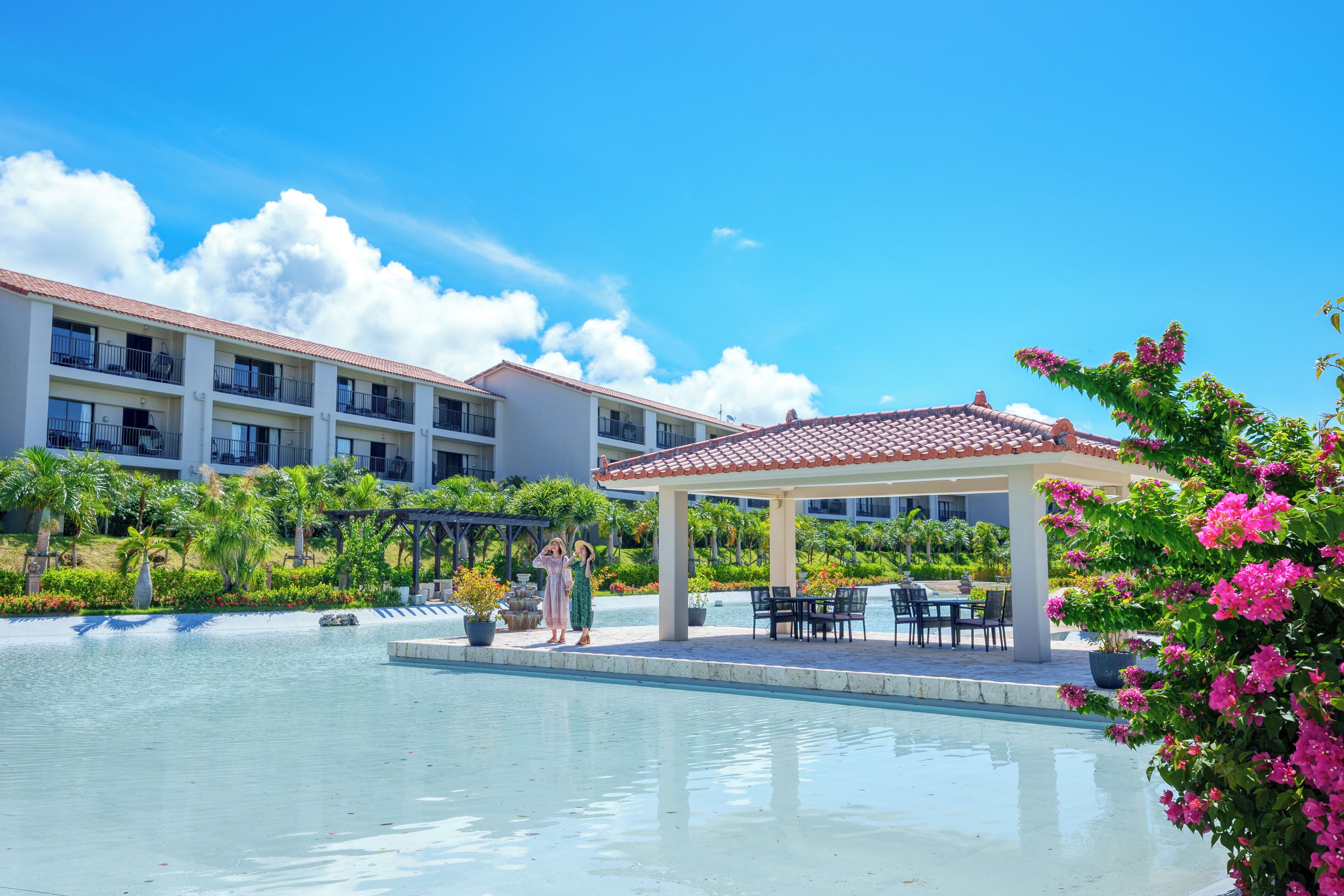 Un hotel con piscina, mobiliario exterior y una zona cubierta con vistas a la piscina.
