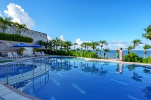 Relax by the serene pool surrounded by lush greenery and ocean views.