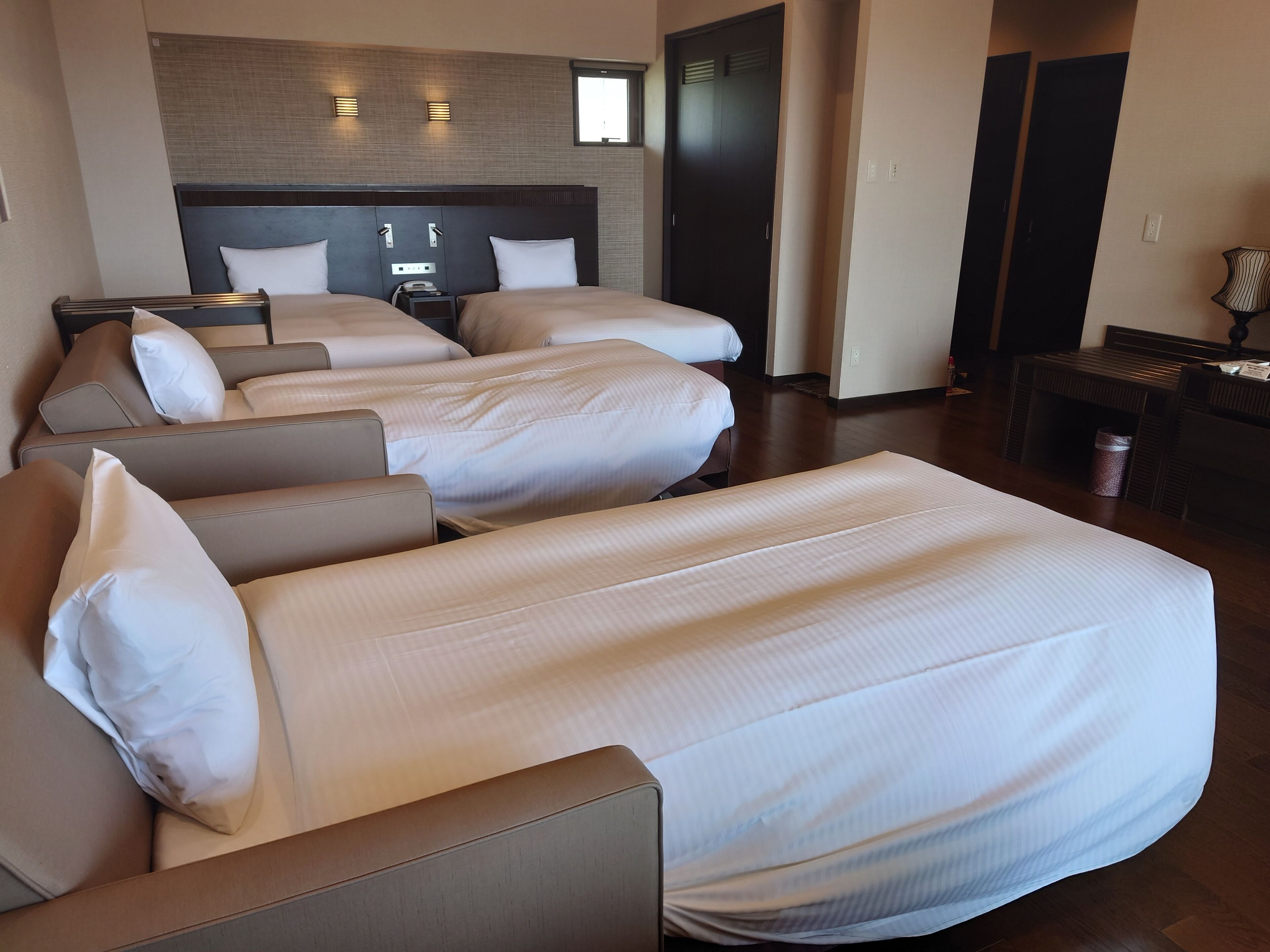 A hotel room with two beds, a desk, and a wardrobe.