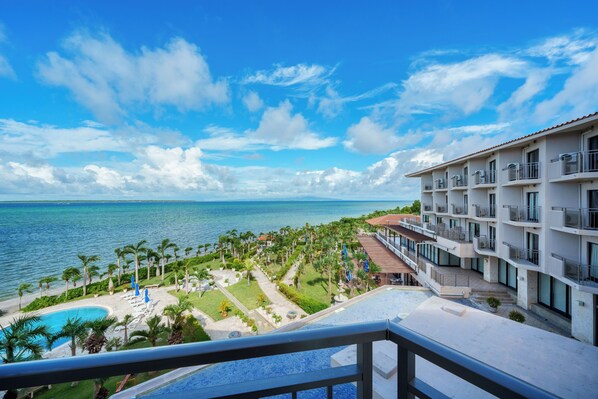 A hotel with a pool, palm trees, and a view of the ocean.