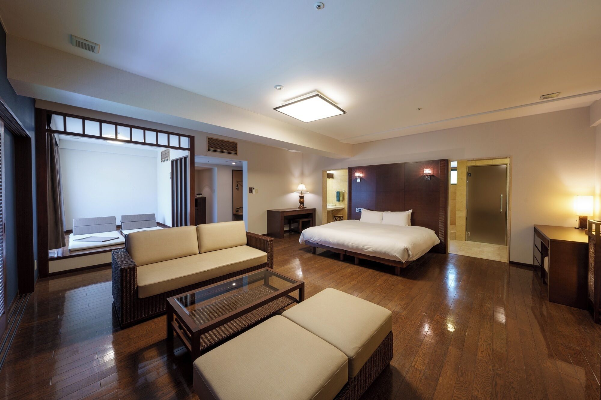 Een hotelkamer met een bed, bank en een glazen bijzettafeltje.