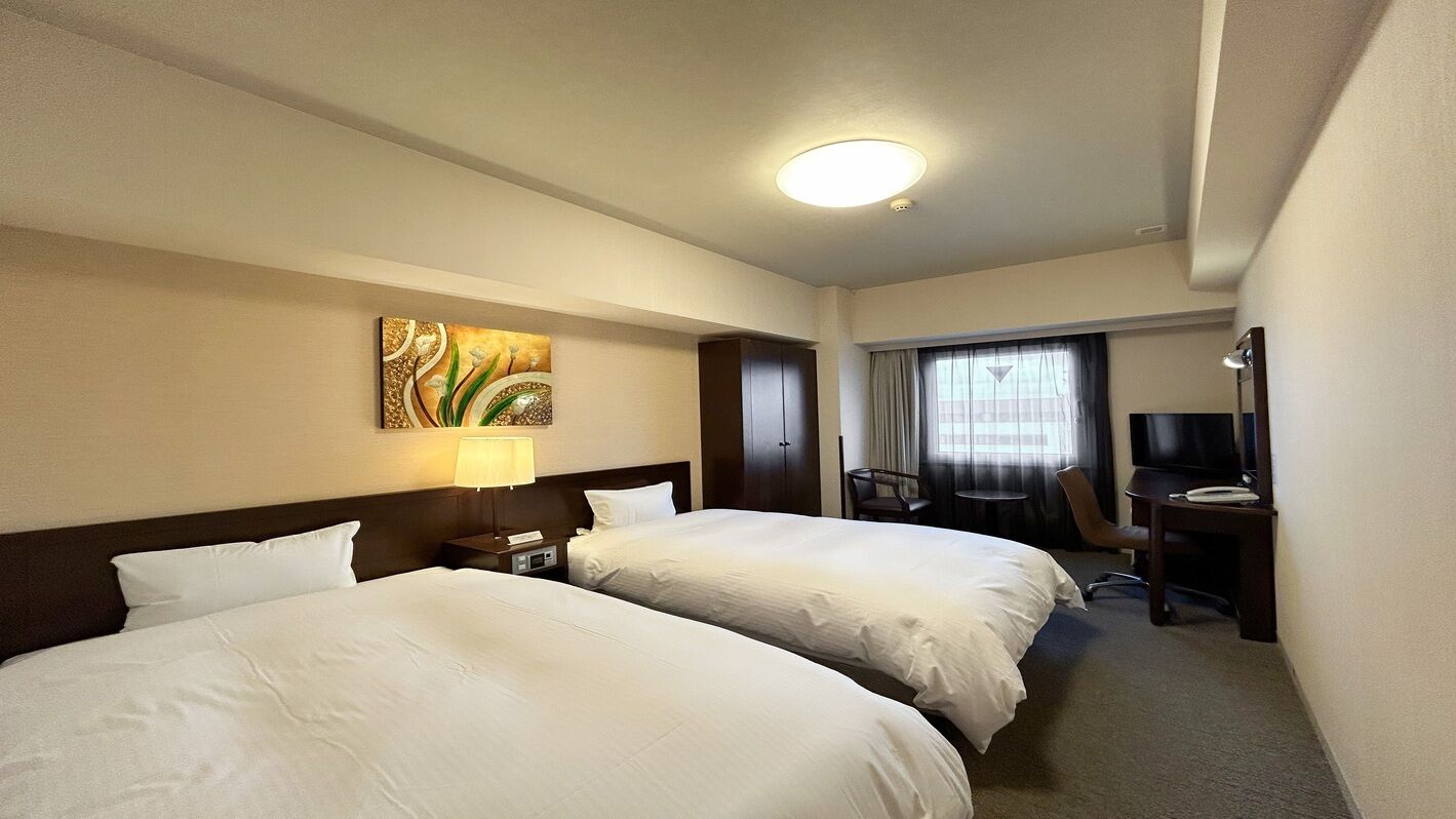 A hotel room with two beds, a desk, a chair, a TV, and a painting on the wall.
