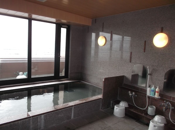 A modern bathroom with a glass-enclosed hot tub, a large mirror, and a shower area.