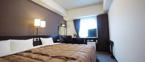 A hotel room with a large bed, a desk, a chair, a television, and a mirror.