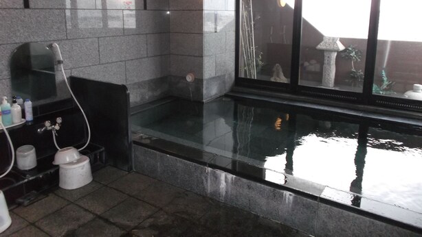 A modern bathroom with a glass-enclosed hot tub, a mirror, and a window with a view of the outside. - Hotel Route-Inn Hirosaki Ekimae (Hirosaki)