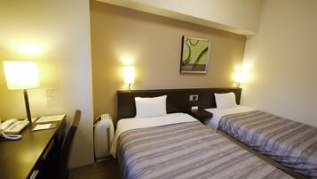A hotel room with two beds, a desk with a telephone, and a chair.