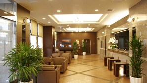 A hotel lobby with seating areas, a reception desk, and large potted plants. - Hotel Route - Inn Chitose Ekimae (Chitose)