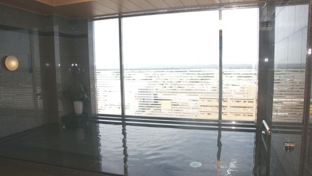 A modern indoor pool area with a large window offering a city view. - Hotel Route - Inn Chitose Ekimae (Chitose)