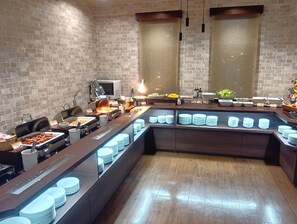 A buffet setup with various food items and a modern brick wall background. - Hotel Route Inn Abashiri Ekimae (Abashiri)