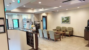 A reception area with a counter, chairs, a vending machine, and a large window. - Hotel Route Inn Abashiri Ekimae (Abashiri)