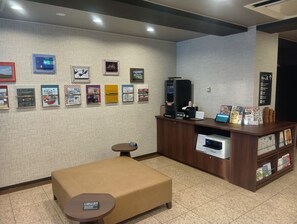 A hotel lobby with a reception desk, a self-service coffee machine, and a seating area with a small table. - Hotel Route Inn Abashiri Ekimae (Abashiri)