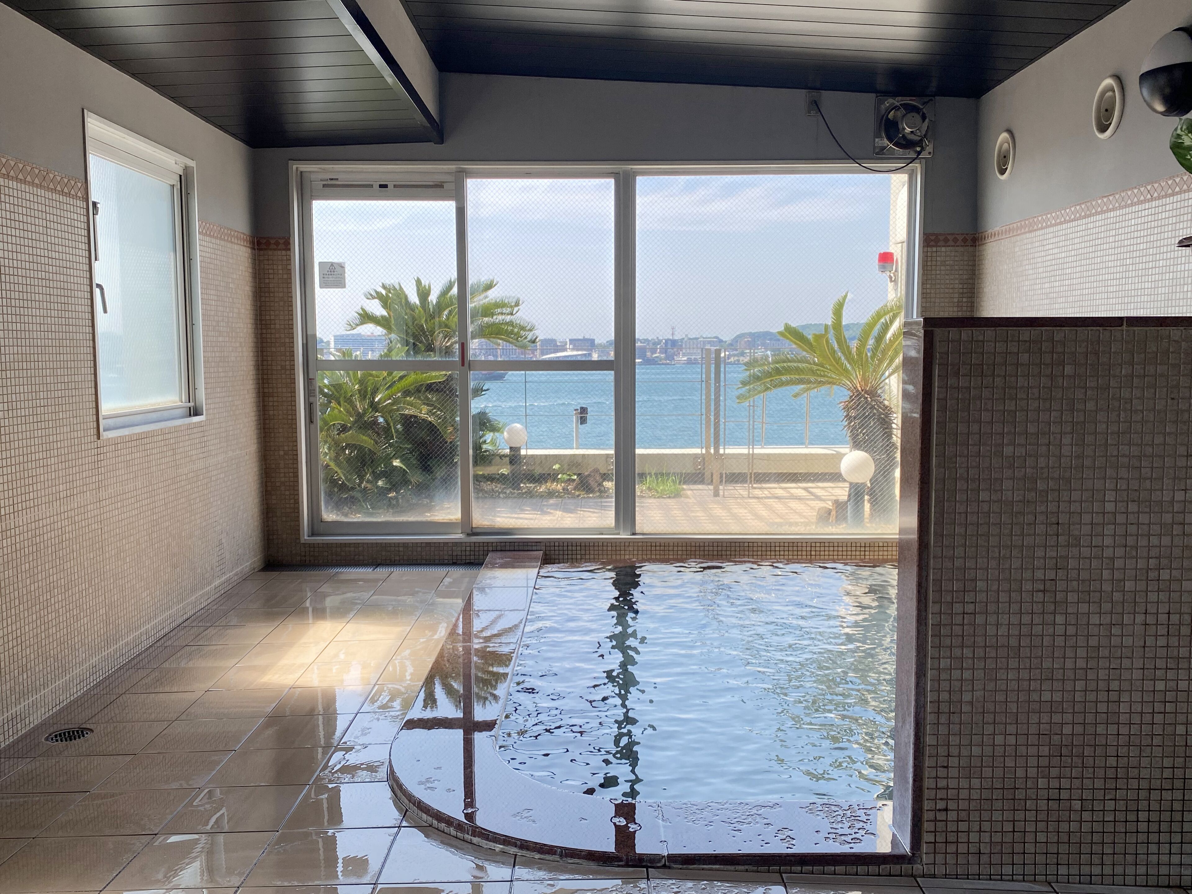 A room with a large window, a tiled floor, and a pool.