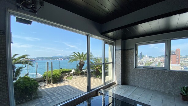 En modern inredning med stora fönster, en pool med glasväggar och utsikt över havet och stadsbilden.
