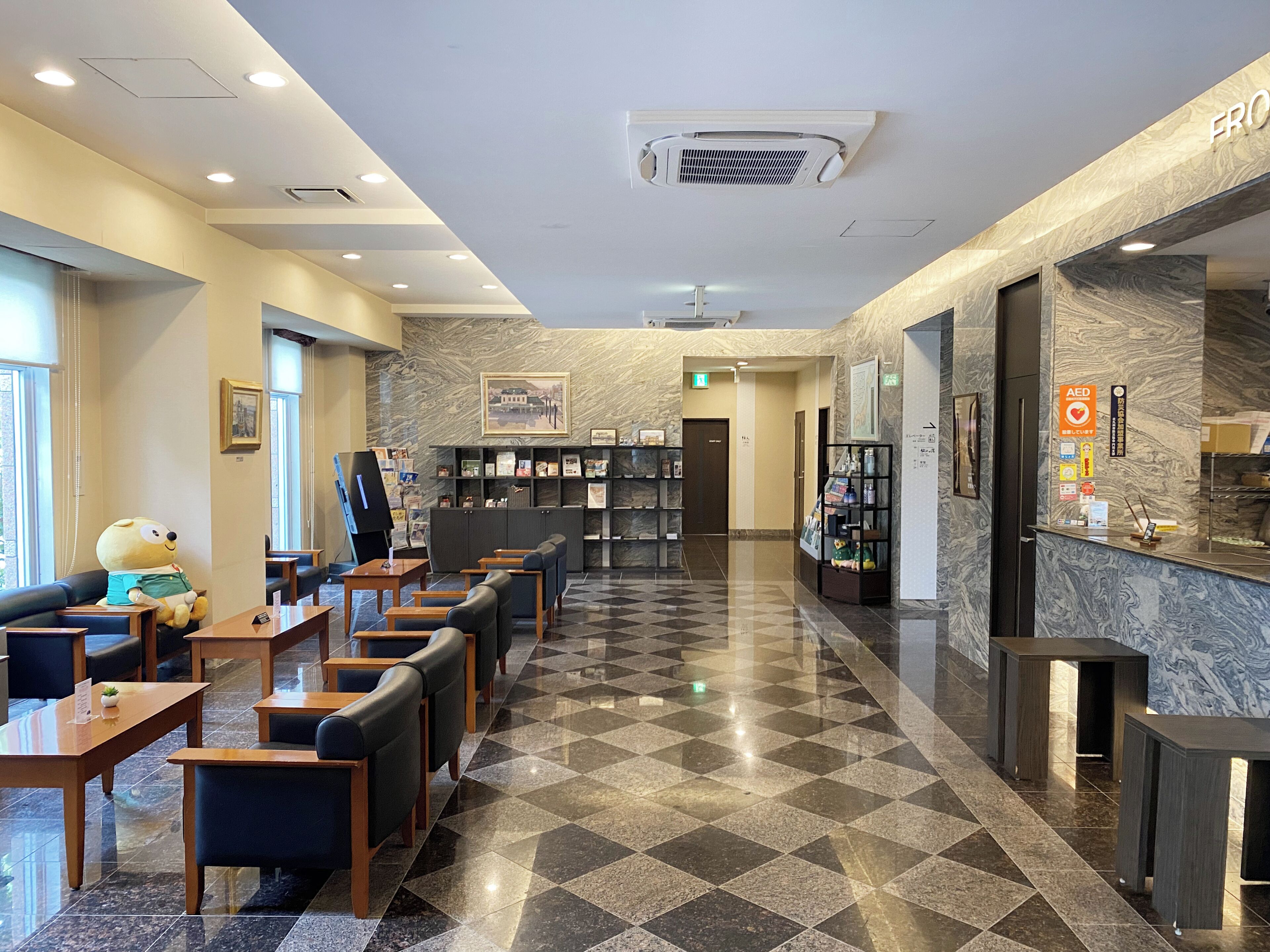 Um saguão de hotel com balcão de check-in, área de estar e mesa de recepção.