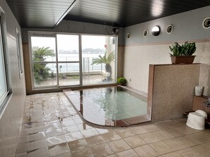 Ein Badezimmer mit großem Fenster, kleinem Pool und einer Topfpflanze.