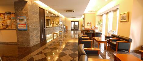 Una hall d'hotel con banco accettazione, area relax e reception.