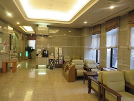 Um hall de hotel com balcão de recepção, área de estar e máquina de café.