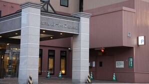 Entrada de hotel com placa em japonês, sinalização de estacionamento e portão.