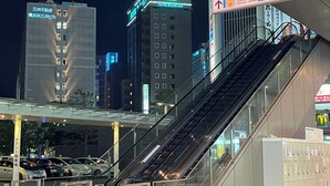 An indoor escalator leading to a modern building with illuminated signage, including a hotel and a bus terminal. - Hotel Route Inn Hakata Ekimae (Fukuoka)