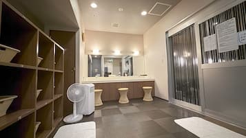 A hotel bathroom with a large mirror, a sink, and a fan.