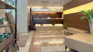 A modern hotel lobby with a reception desk, seating area, and a staircase leading to the upper floors. - Hotel Route Inn Hakata Ekimae (Fukuoka)
