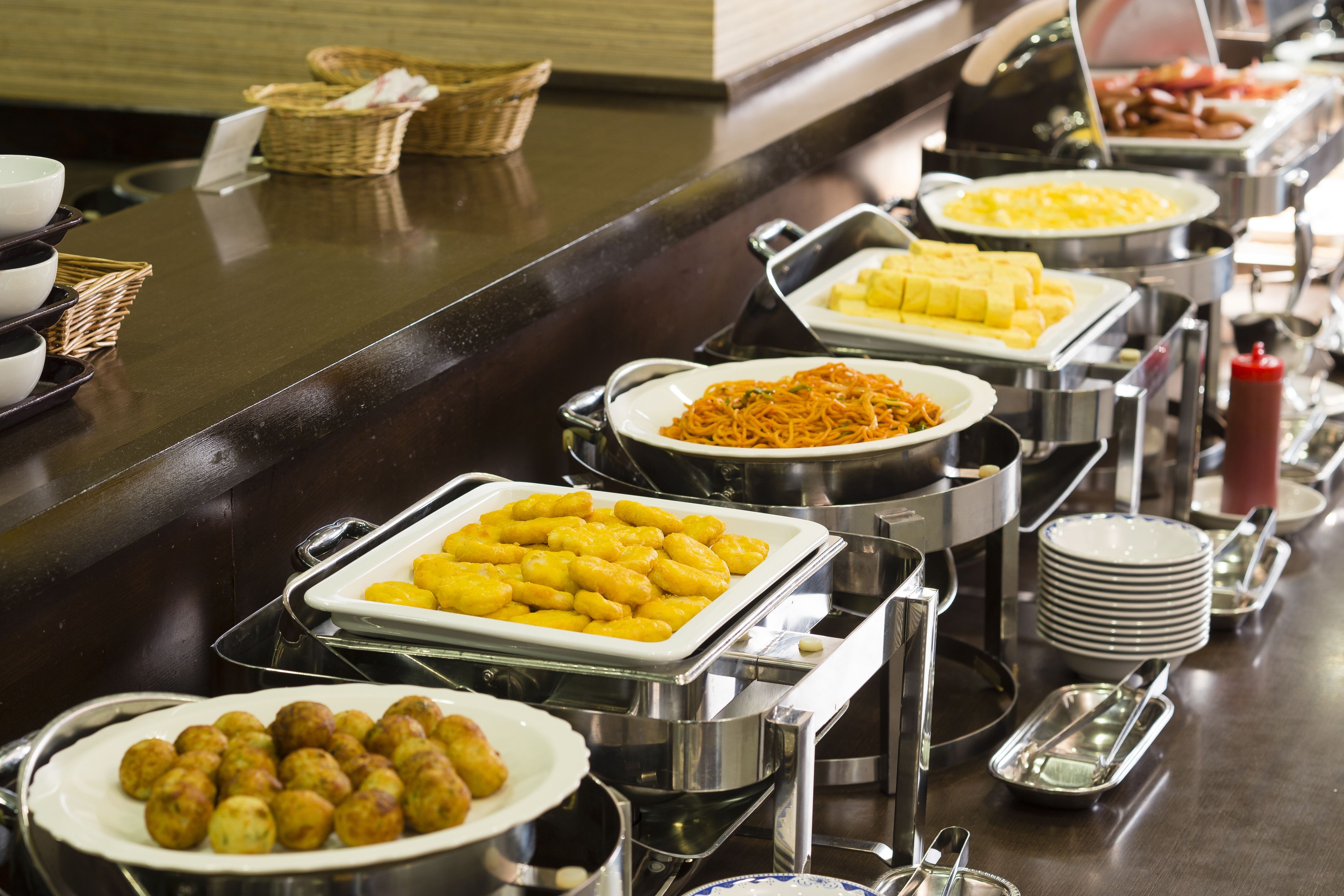 A buffet with various dishes including dumplings, yellow custard, and other prepared foods.
