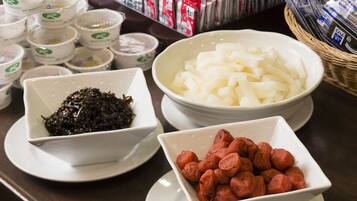 A table with bowls of food, including seaweed, white noodles, and sausages.