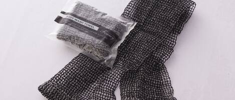 A black mesh body wash towel with a label, placed on a white surface.