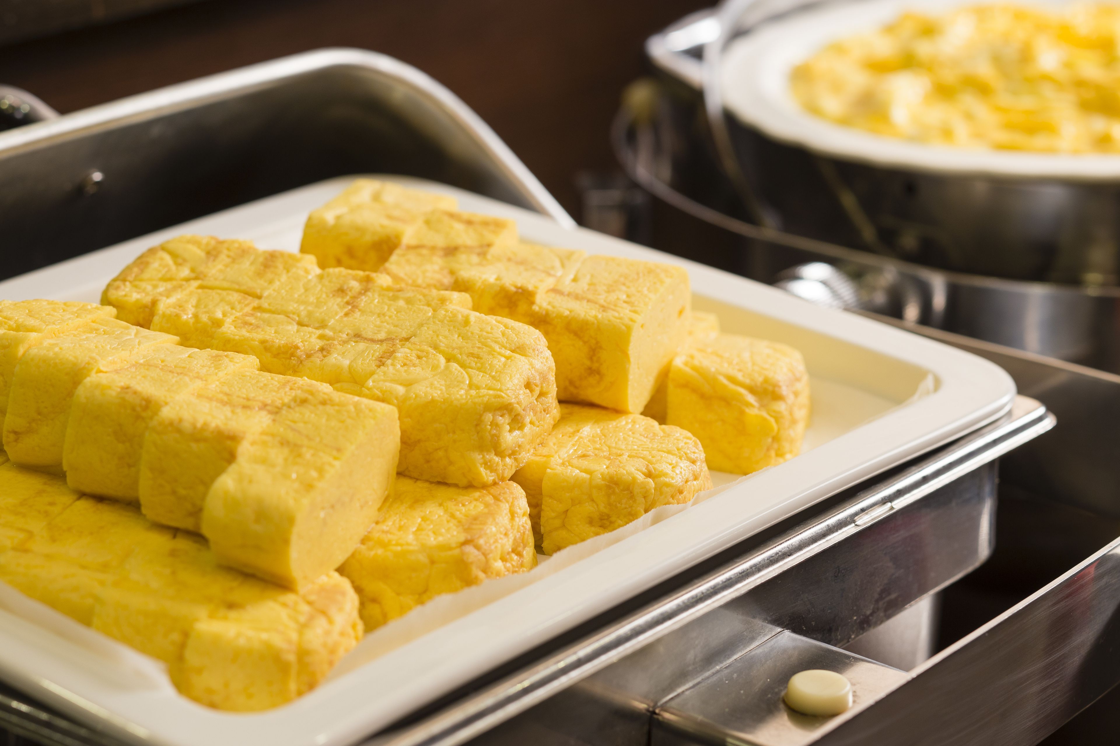 Un vassoio con cubetti di crema pasticcera gialla in un'area buffet.