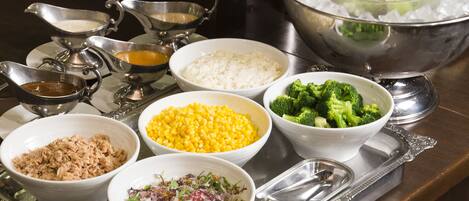 A tray with various food items including rice, corn, broccoli, and a salad.