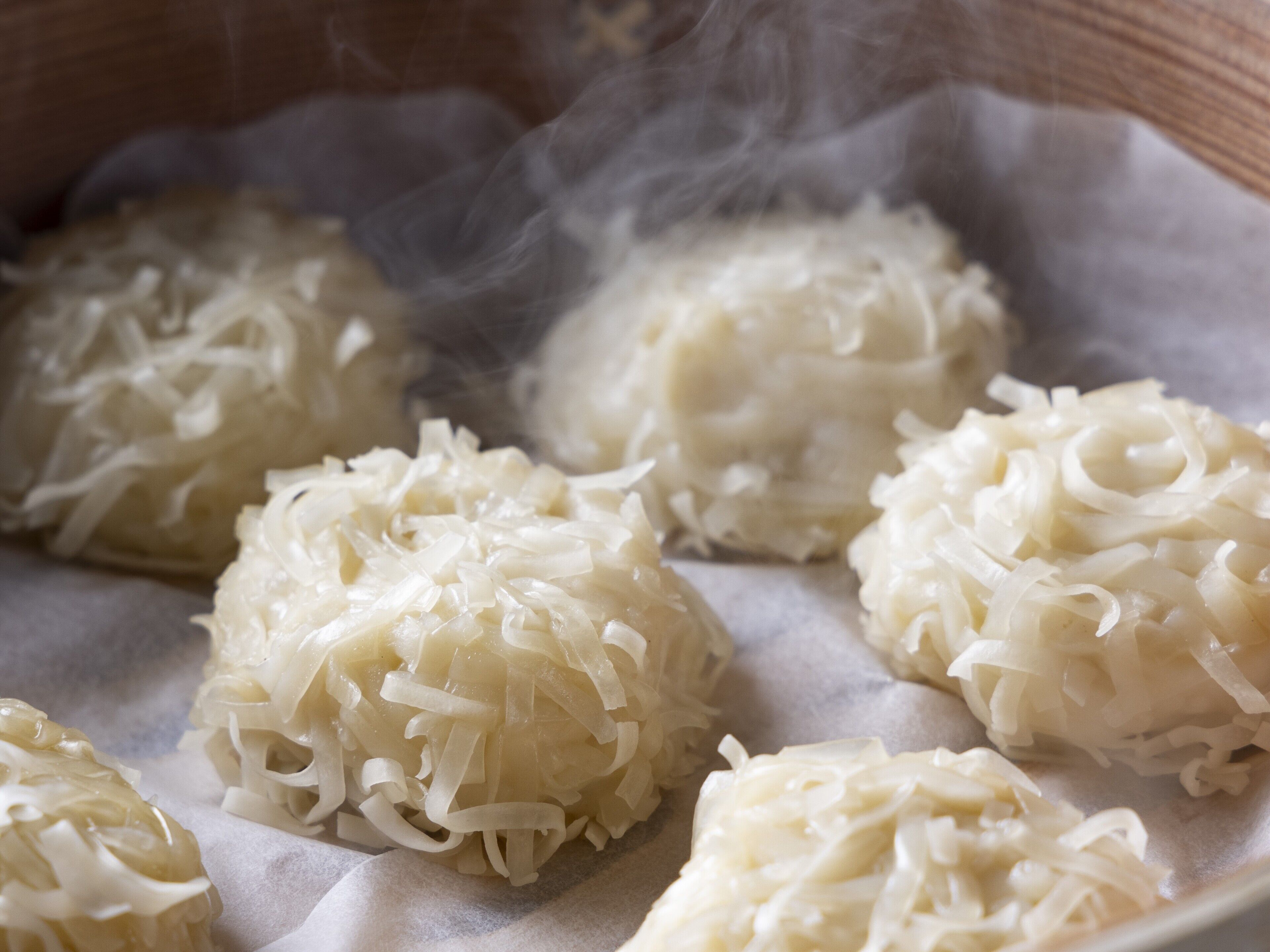 A close-up of steamed rice balls with shredded ingredients, possibly in a traditional cooking setting.