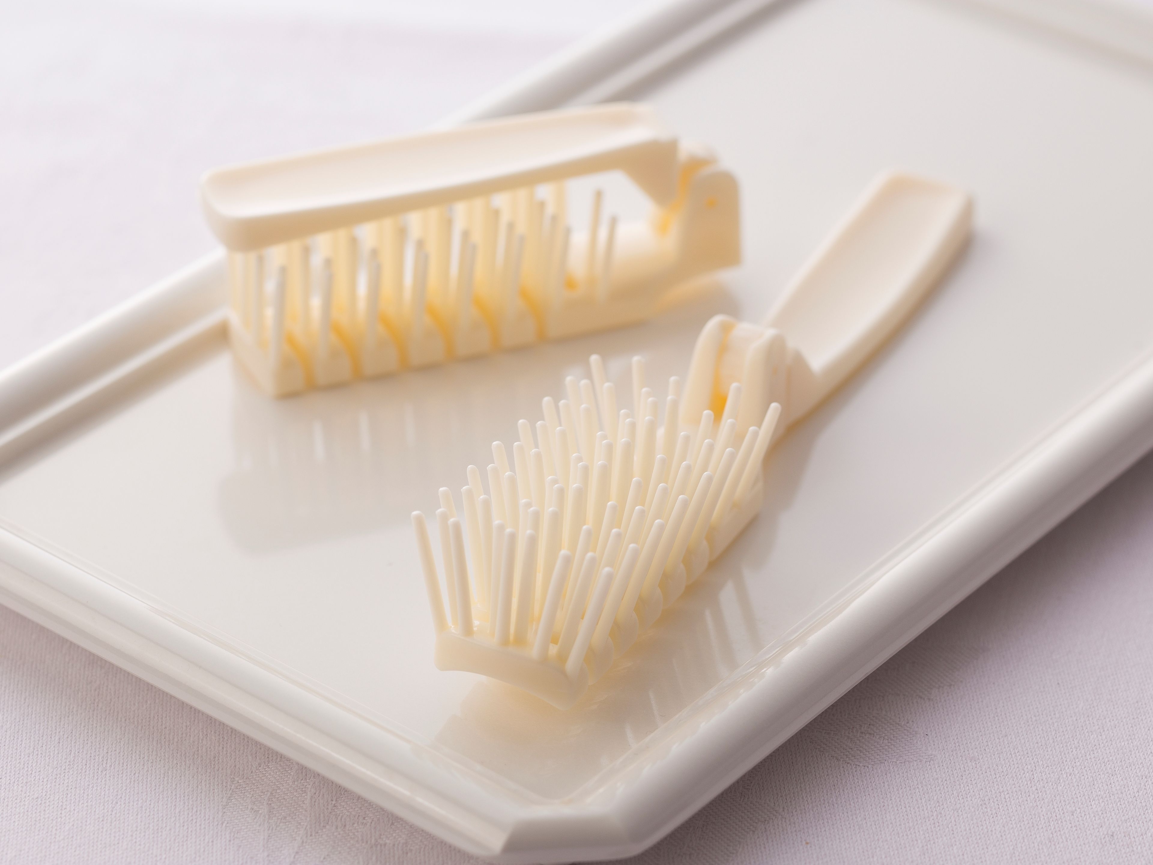 Two white toothbrushes on a white rectangular tray.