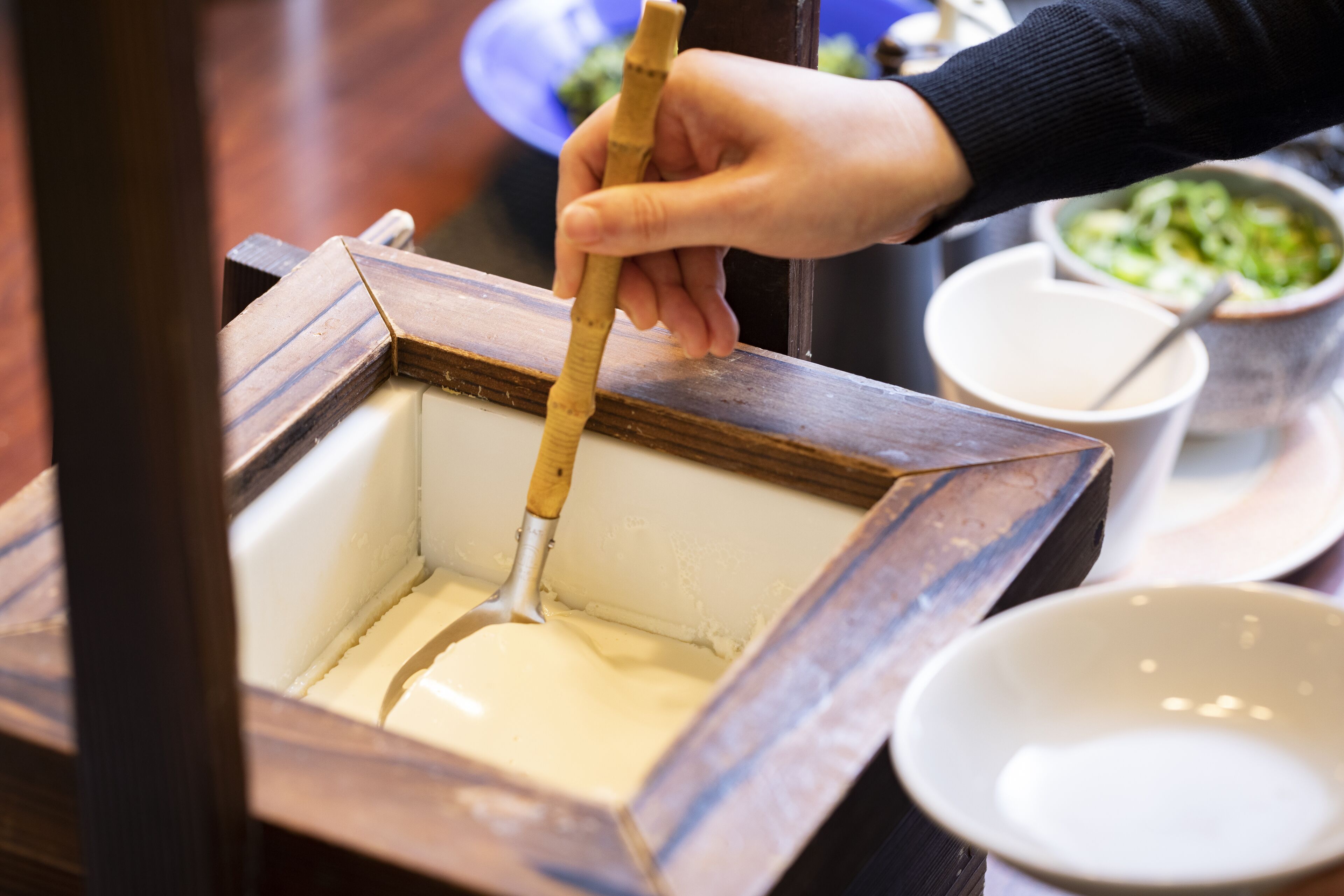 A hand scooping a creamy substance from a container.