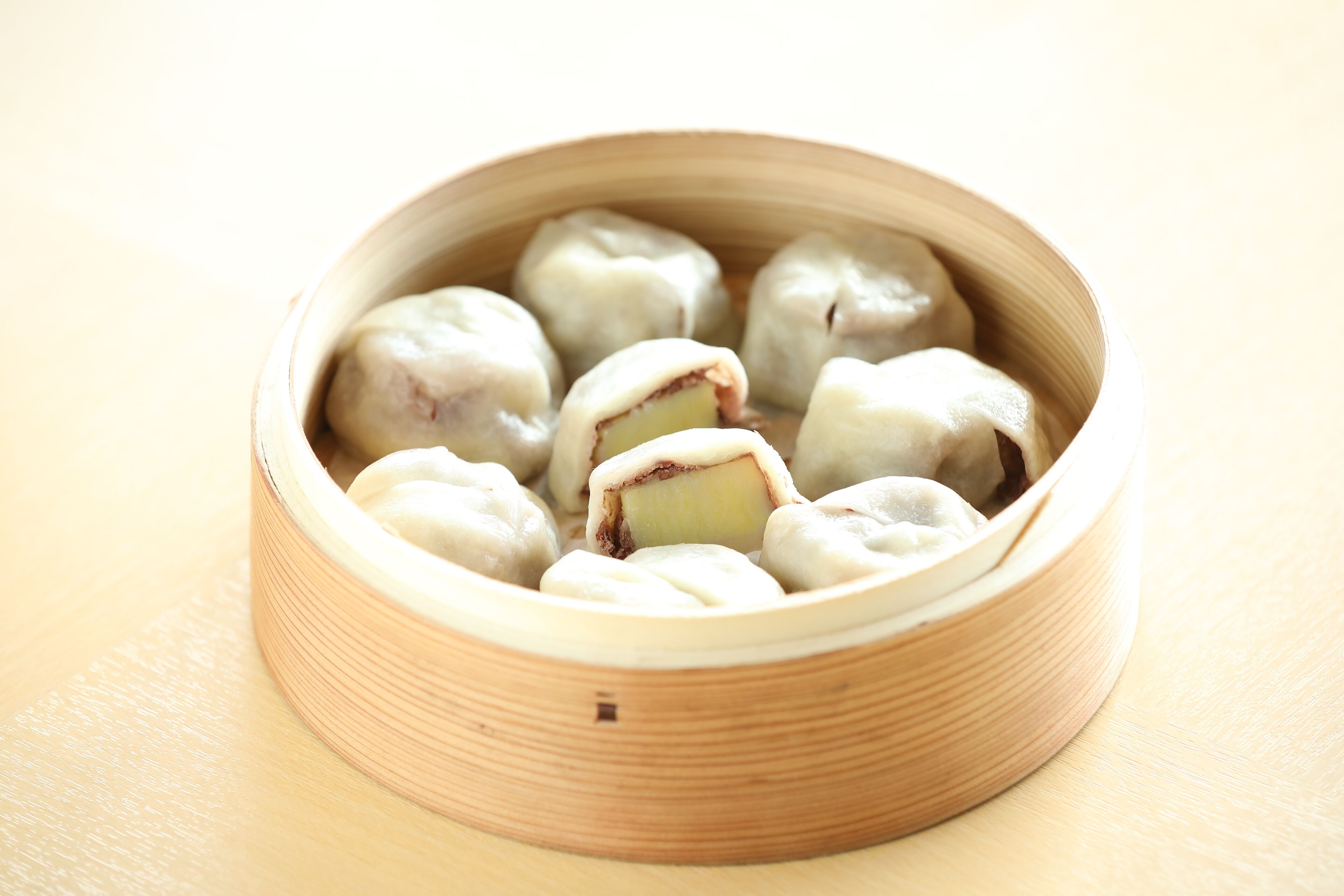 A bamboo steamer containing several dumplings.