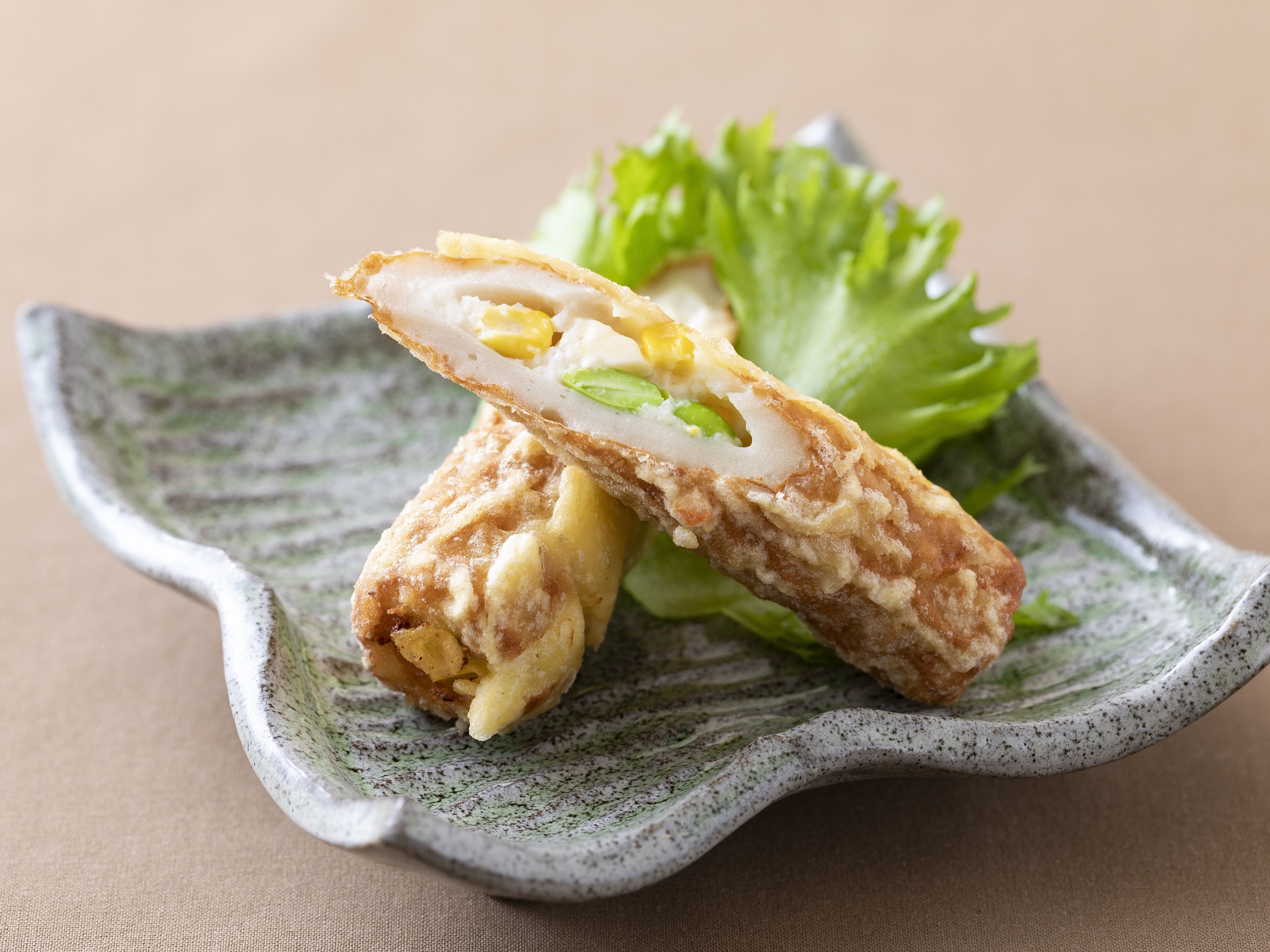 A fried food item on a ceramic plate with a green leafy garnish.