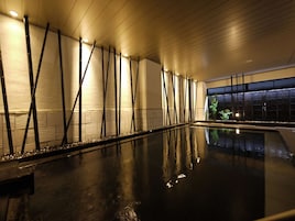 Una piscina interna dal design moderno, con una vasca lunga e stretta e una serie di luci verticali lungo le pareti.