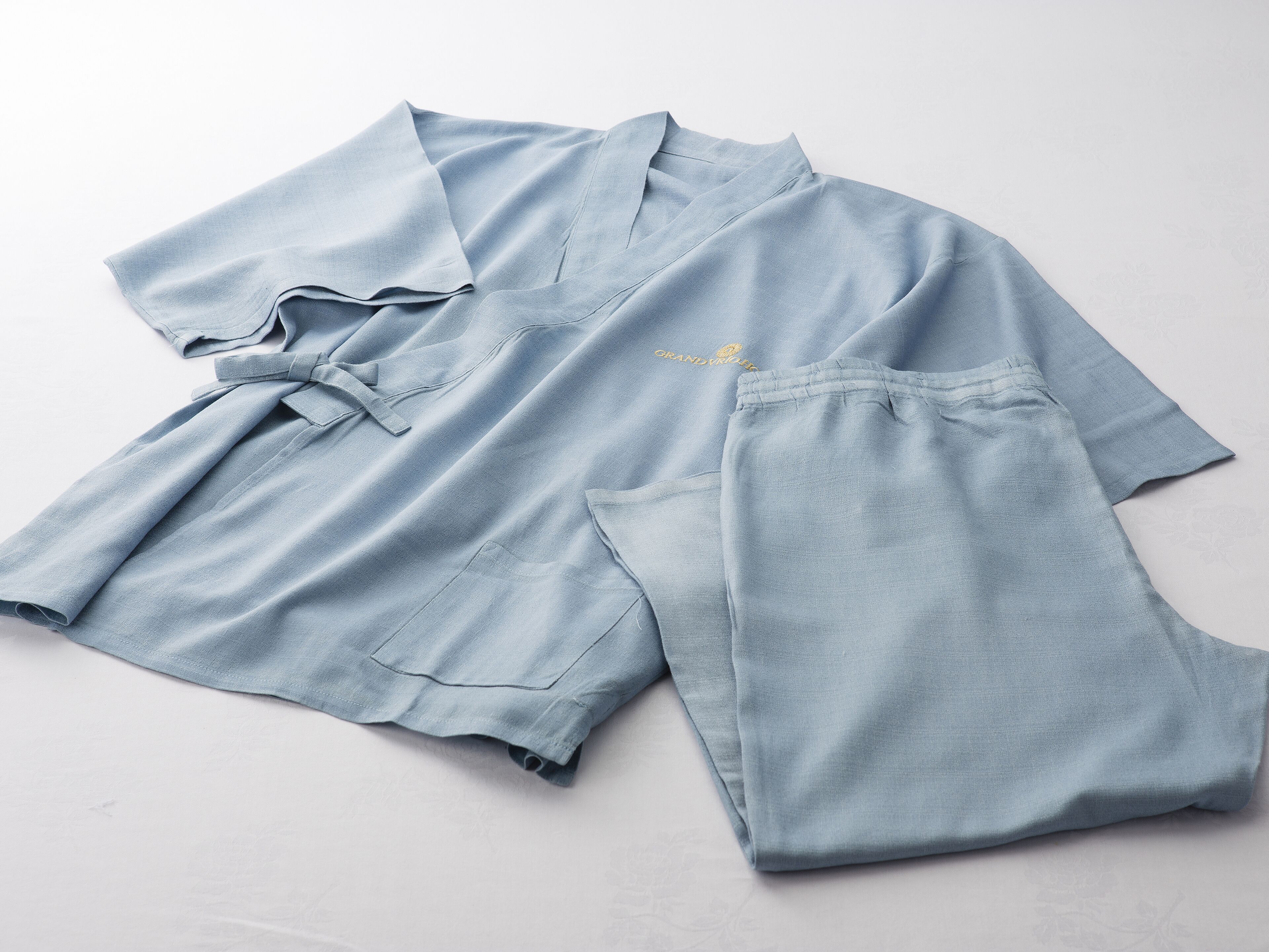 A neatly folded light blue shirt and matching shorts on a plain surface.