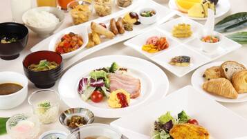 A variety of breakfast dishes including eggs, ham, and pastries, arranged on a table with several small bowls and glasses of beverages.