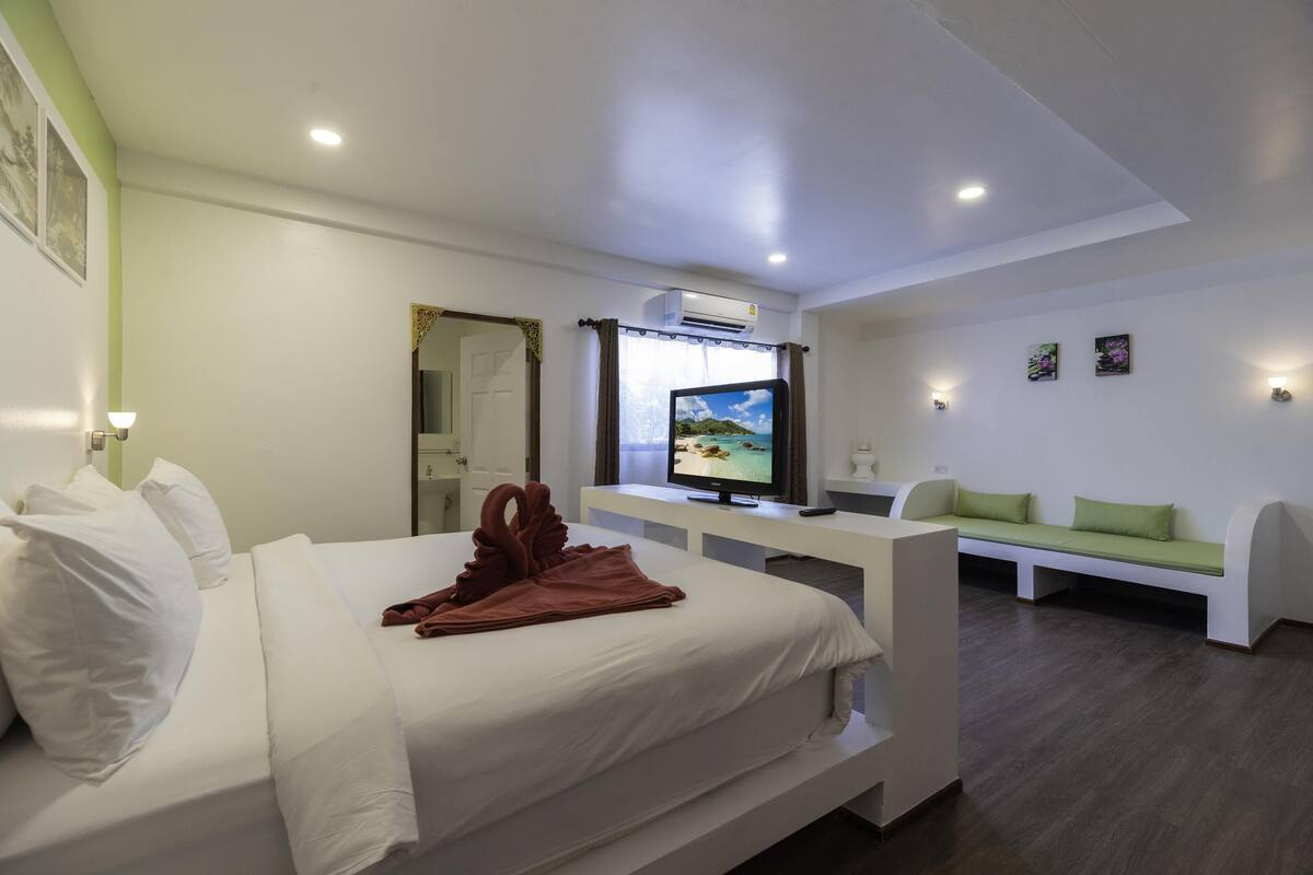 A hotel room with a bed, a TV, a sofa, and a desk.