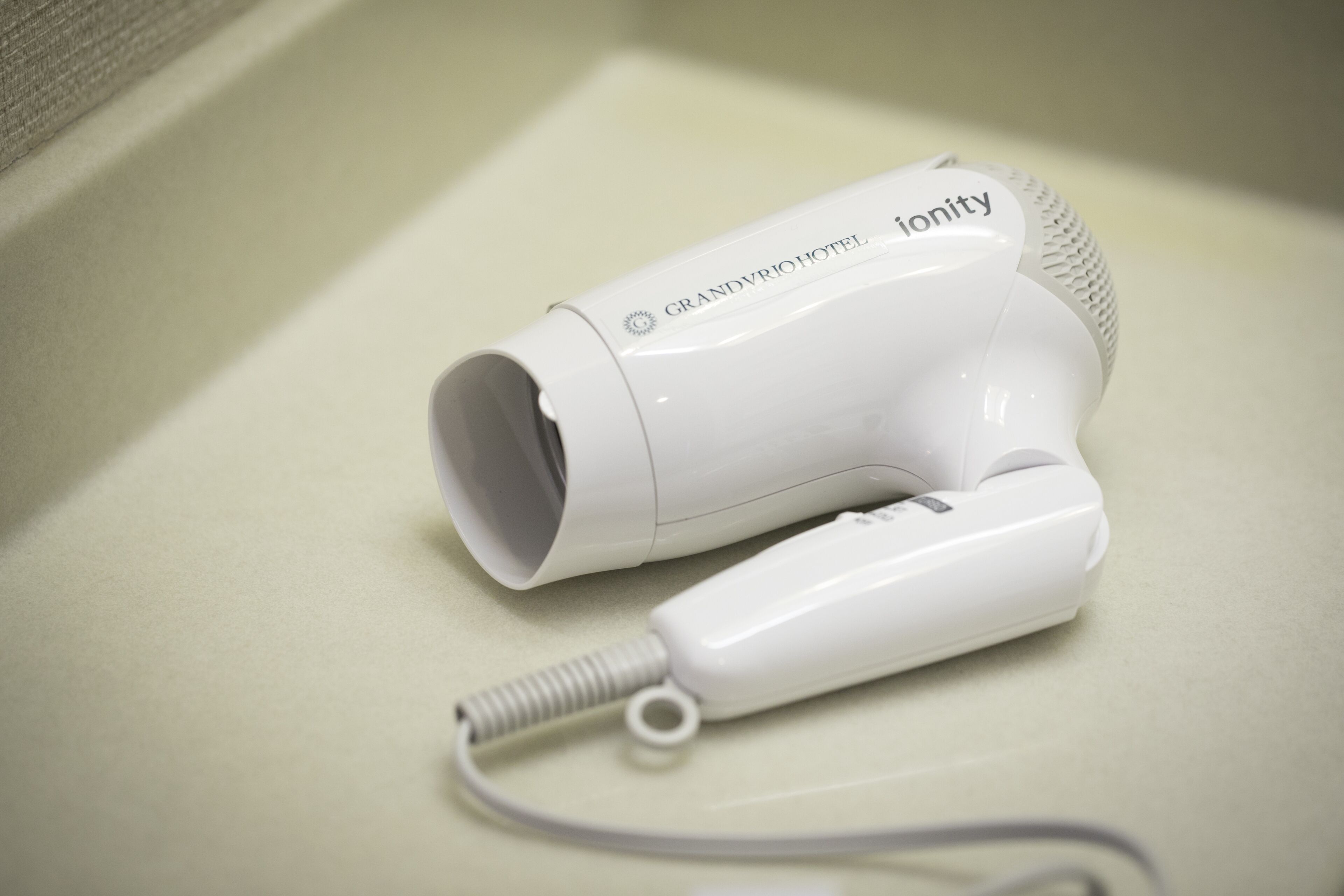 A white hair dryer with the brand name "ionity" and "GRANDVIRIOHOTEL" visible on it.