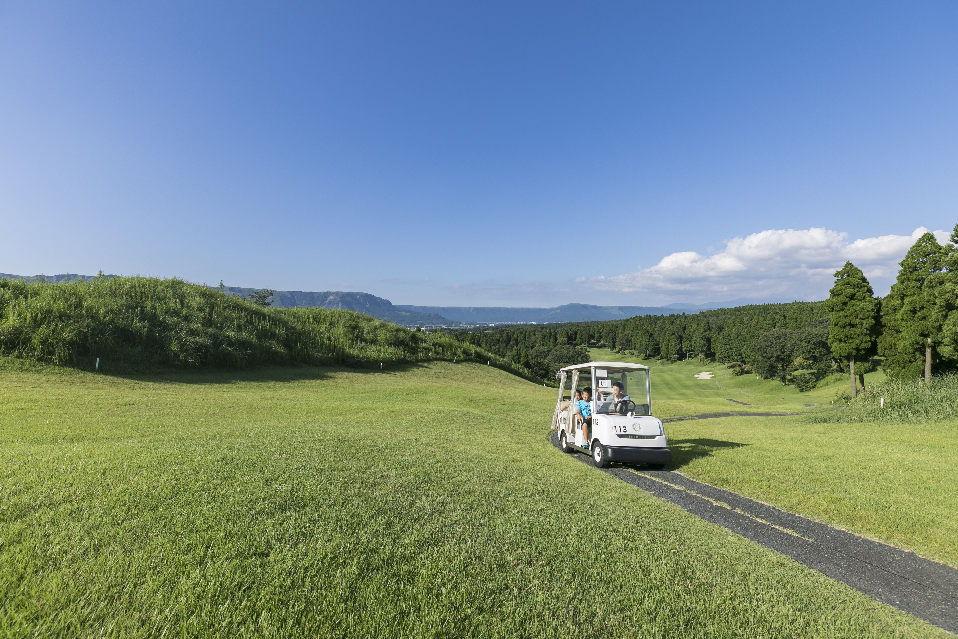 A golf cart on a green field with a clear sky.
