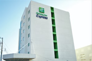 Edificio de Holiday Inn Express con diseño moderno, destacando un marcado acento verde en la fachada.
