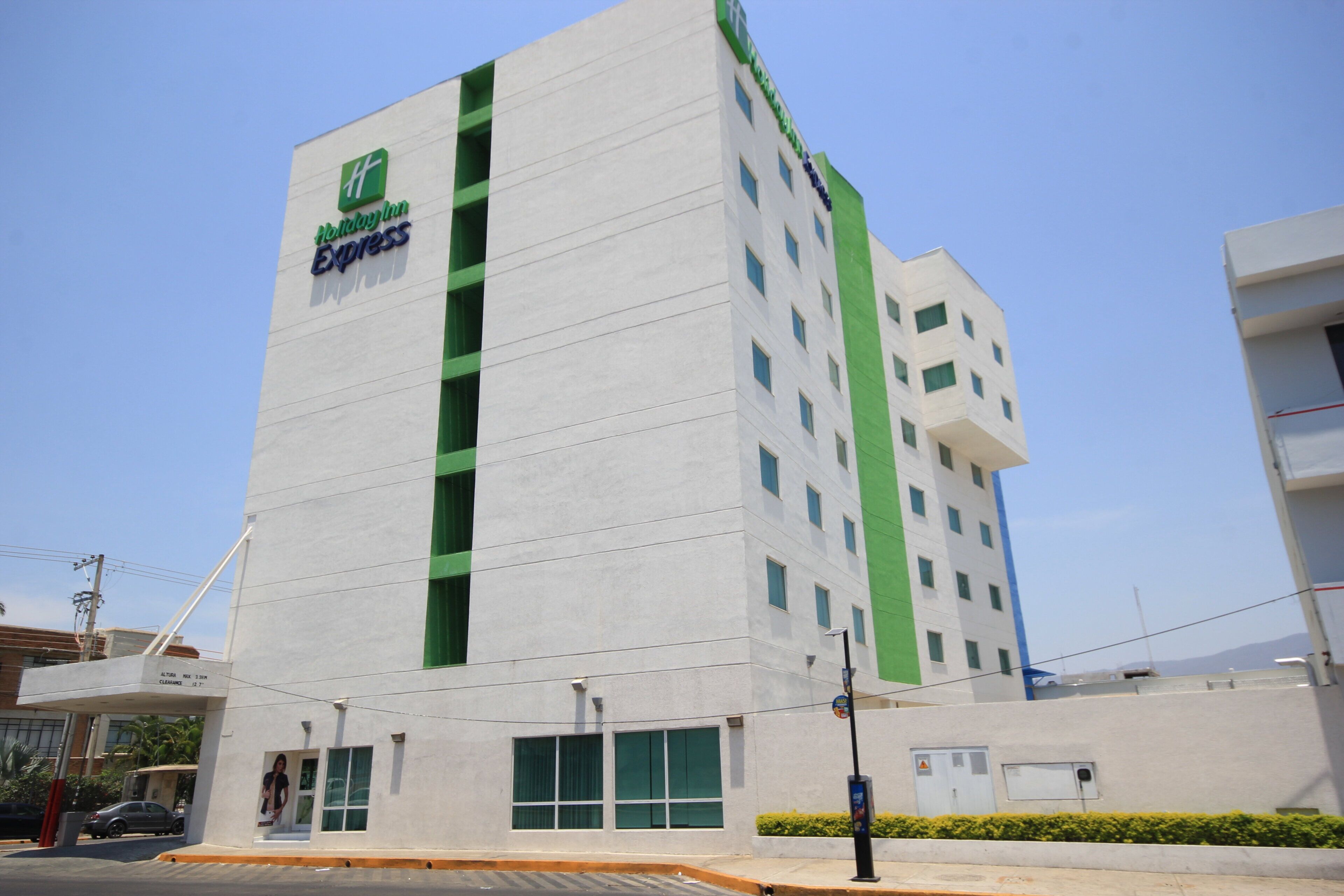 Un edificio alto con facciata verde e bianca, con il logo Holiday Inn Express.