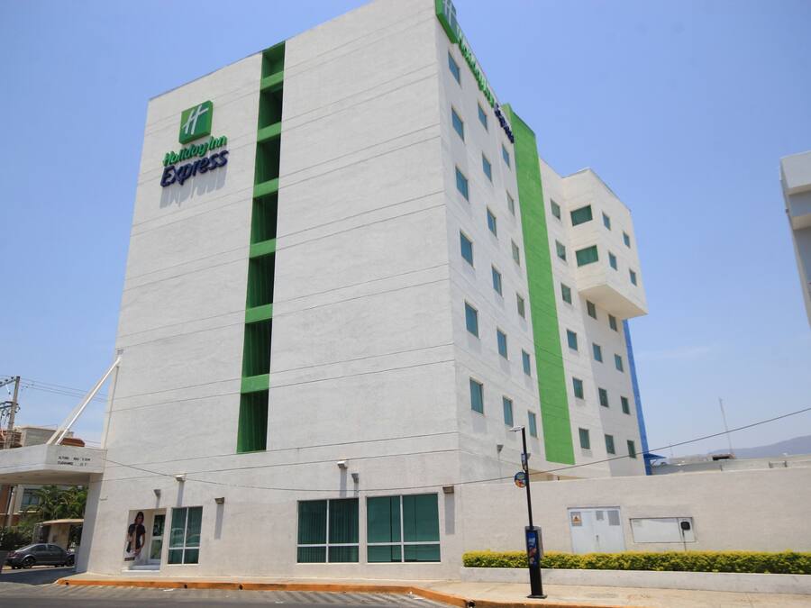 Un edificio alto con facciata verde e bianca, con il logo Holiday Inn Express.