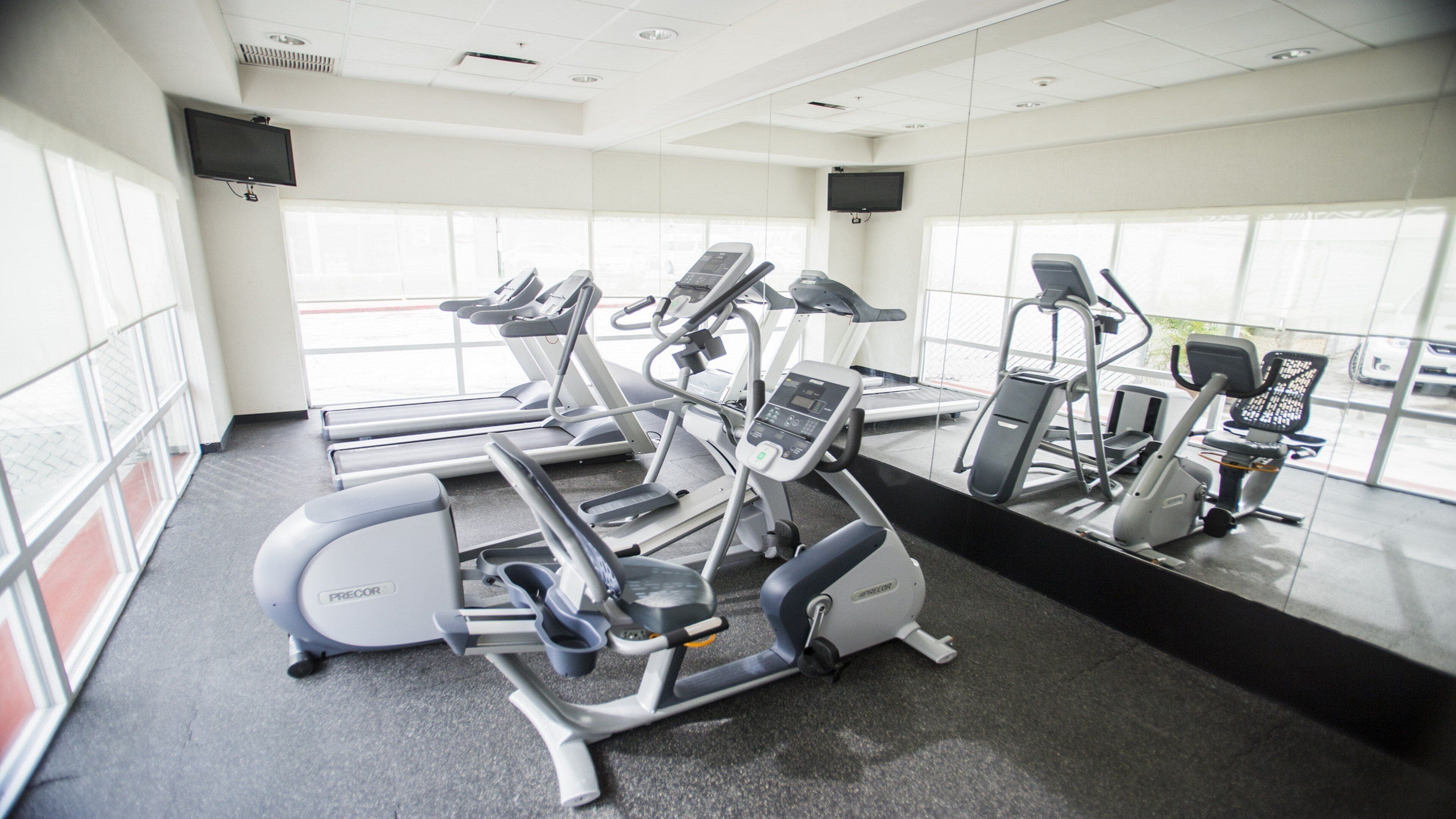 A gym with various exercise equipment, large windows, and a clean, modern design.