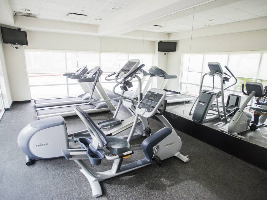 A gym with various exercise equipment, large windows, and a clean, modern design.