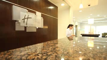 Una recepción con mostrador de mármol, una mujer de pie y un letrero que dice 'Holiday Inn Express'.