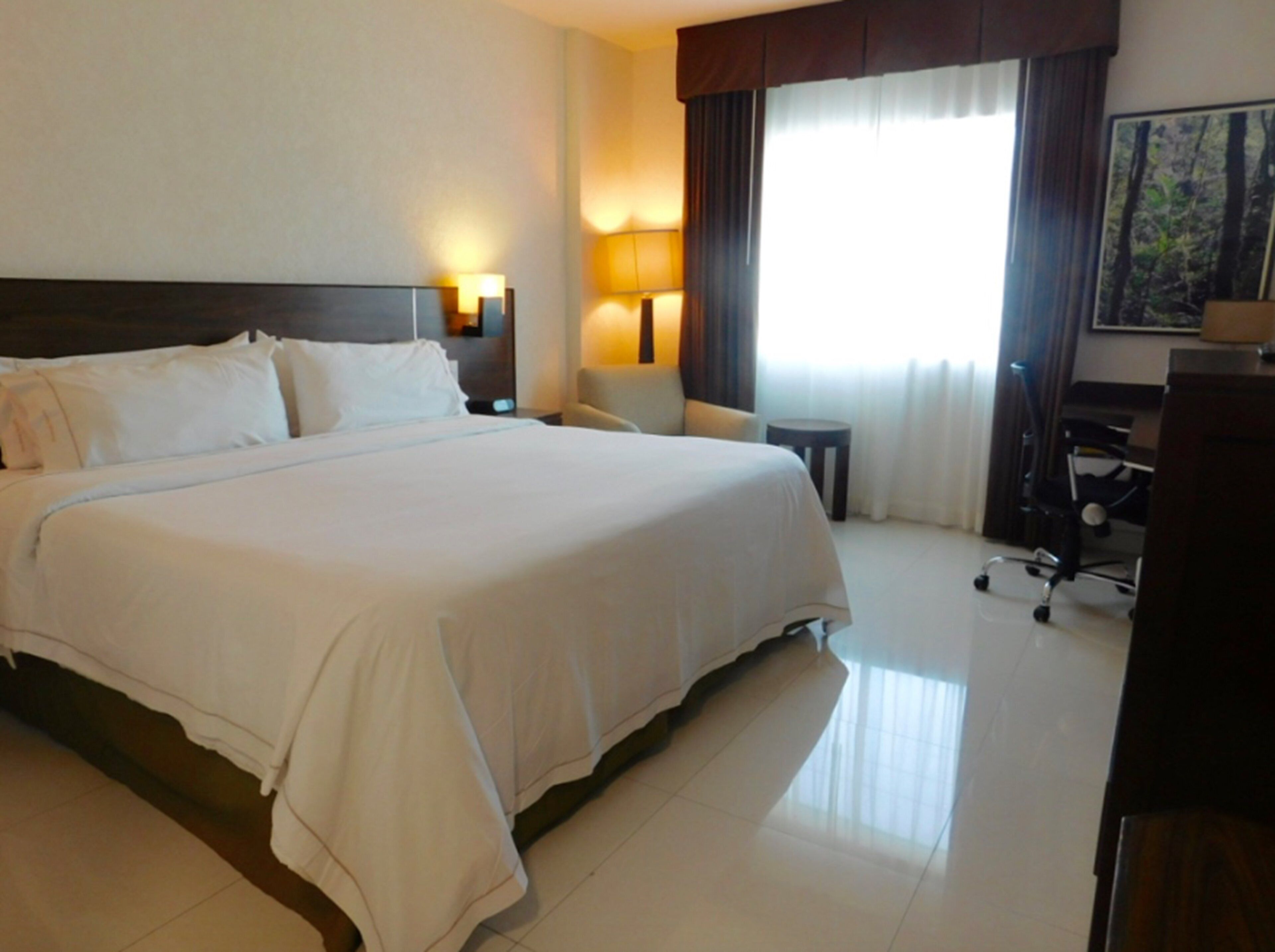 Een hotelkamer met een groot bed, twee bedlampen, een bureau en een stoel.